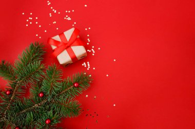 Noel kompozisyon tebrik kartı. Kırmızı arka planda altın yıldızlı konfeti ve Noel süslemesi olan el sanatları kağıdından hediyeler. Üst manzara, düz uzanma