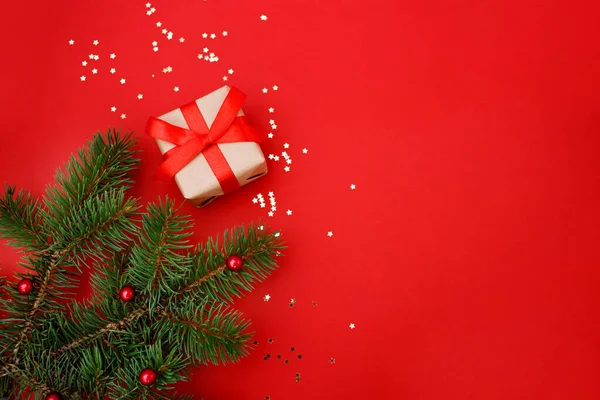 Noel kompozisyon tebrik kartı. Kırmızı arka planda altın yıldızlı konfeti ve Noel süslemesi olan el sanatları kağıdından hediyeler. Üst manzara, düz uzanma