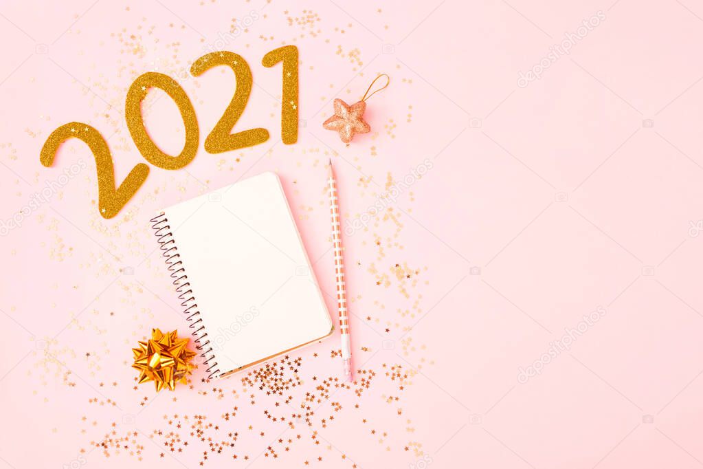 New Year goal list 2021. Desk with notebook for writing about plan listing of new year goals and resolutions setting on pink pastel background with star confetti. Change and determination concept