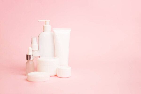 Белые банки косметики на розовом пастельном фоне. Аксессуары для ванной Концепция ухода за лицом и телом. Копирование пространства.