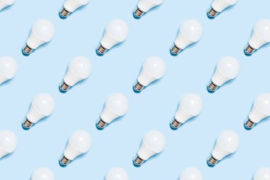 Creative seamless pattern of LED light bulbs on blue background. Energy saving concept. Minimalism, top view, flat lay,pattern, packaging