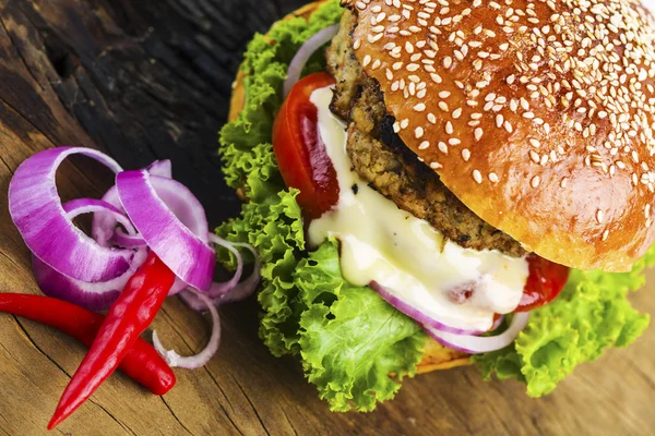 Ahşap masa üzerinde sebzeler ile lezzetli Hamburger — Stok fotoğraf