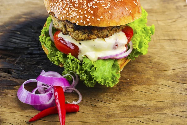 Ahşap masa üzerinde sebzeler ile lezzetli Hamburger — Stok fotoğraf