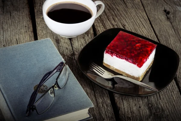 Vintage book reading cup of coffee and cheesecake on grungy wooden background — Stock Photo, Image