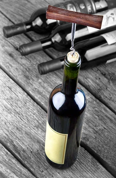 Sticlă de vin pe o masă de lemn care iese din mulțime — Fotografie, imagine de stoc
