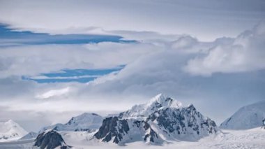 Kar altında beyaz-mavi buzdağının zamanı geldi çattı. Kümülüs bulutları buz dağının zirvesinde akıyor.