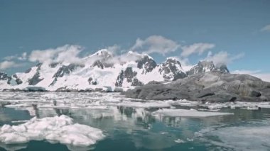 Antarktika eriyen buzdağları okyanus körfezinde kaya kıyı anteniyle yüzer. Çevre ekolojisi
