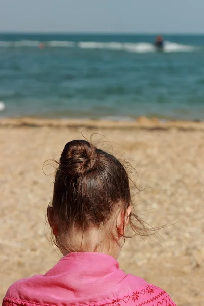 Klein meisje zittend op het strand — Stockfoto