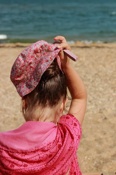 Liten flicka sitter på stranden — Stockfoto