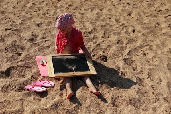 Bambina seduta sulla spiaggia e disegno — Foto Stock