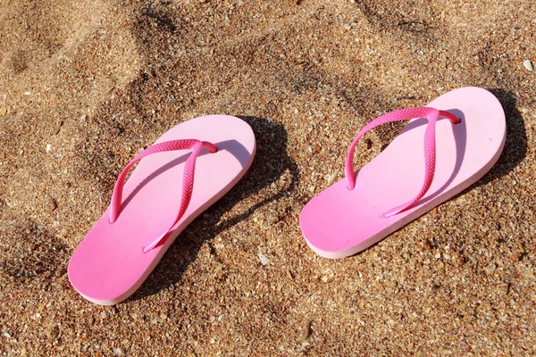 Children's pink flip flops on the sand — Stock Photo, Image