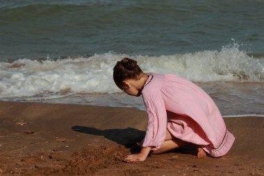 Doğu Kırım 'da deniz kıyısında oynayan güzel küçük bir kızın açık hava görüntüsü.