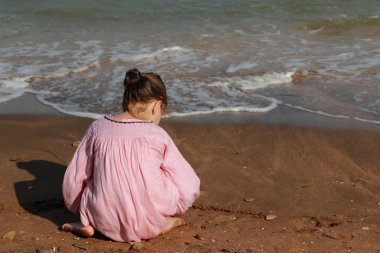 Güzel küçük kız deniz plajı üzerinde oynuyor.