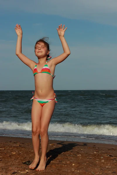 Karadeniz kıyısındaki kumda mayo giymiş mutlu küçük kız oynanıyor ve Doğu Kırım 'da dinleniyor.