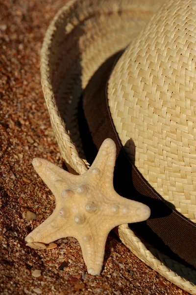 Outdoor image of straw hat and sea starfish over sea sand background from East Crimea, Russia