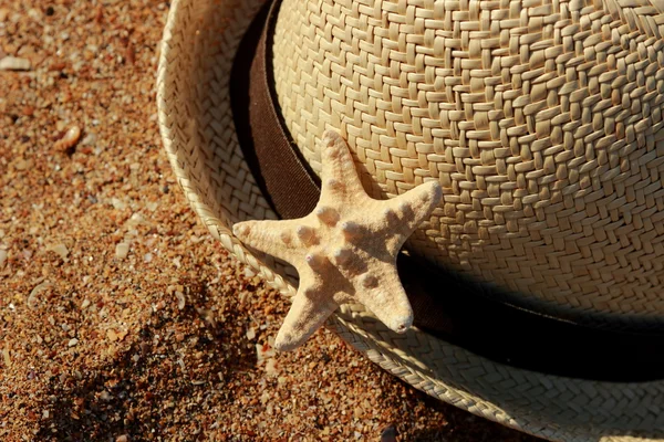 Outdoor image of straw hat and sea starfish over sea sand background from East Crimea, Russia