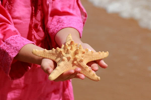 巨大な星の魚を保持ピンクの夏のドレスの小さな女の子 — ストック写真