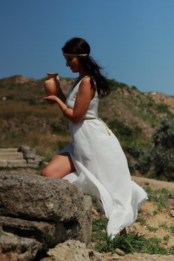 Eski Yunan tarzı giyinmiş çekici genç kadın, Kerch, Kırım gibi arkeolojik kazılarda bir amforo tutuyor.