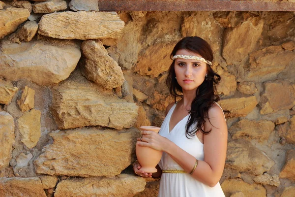 身着希腊风格的白色长裙的年轻貌美的姑娘继续挖掘着古城科尔奇的风采 — 图库照片