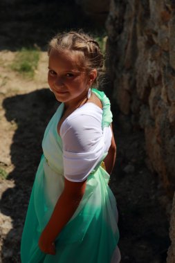 Yunan tuniğiyle gülümseyen büyüleyici genç kız Geroevskoe köyündeki antik Nymphaeum şehrinin arkeolojik sahasında bir zeytin filizi tutuyor, Kerch.