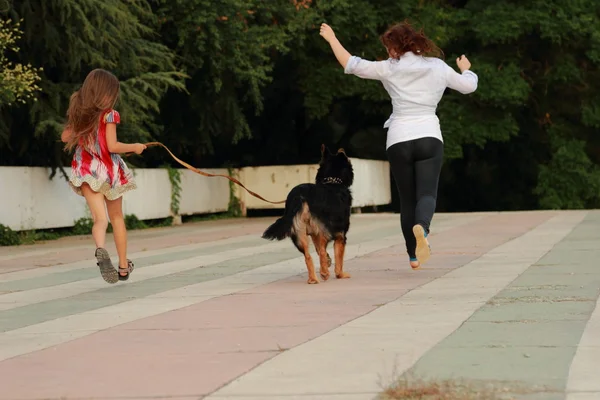 Mor och dotter leker med hund — Stockfoto