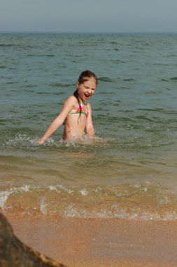 Küçük pembe bir mayo içinde yüzmeye sahilde sıcak yaz günü, arkadan görünüm kızdır