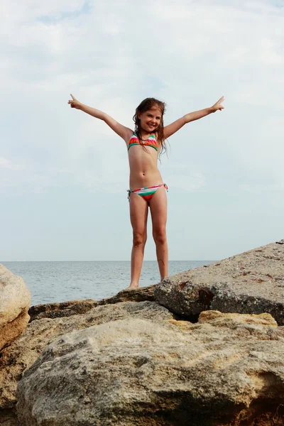 Szczęśliwa Dziewczynka Stojący Strój Kąpielowy Dużą Skale Plaży Tle Niebieski — Zdjęcie stockowe