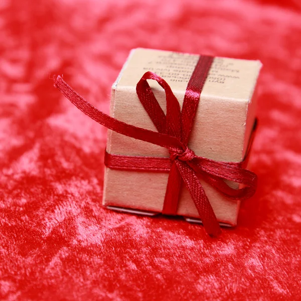 休日のテーマの赤いベルベットのテクスチャ背景に小さな存在ギフト ボックス — ストック写真