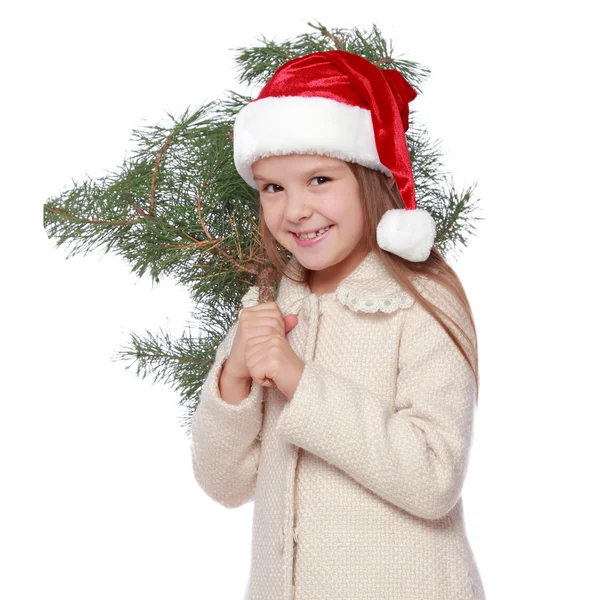 Chica joven positiva en el sombrero de Santa es feliz y riendo con el árbol de Navidad —  Fotos de Stock