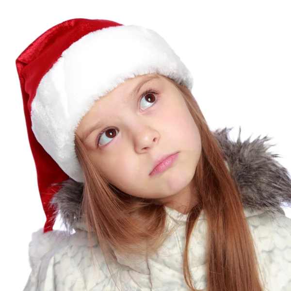 一个开朗的女孩，与圣诞老人的帽子的假日肖像 图库图片