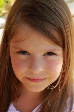 Cute smiling little girl sitting in the summer park bench