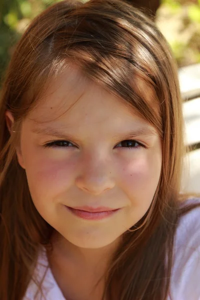 Linda niña sonriente sentada en el banco del parque de verano —  Fotos de Stock