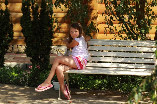 Cute smiling little girl sitting in the summer park bench — Stock Photo, Image