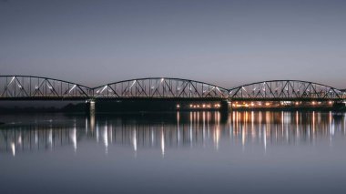 Su yansıtmalı büyük, aydınlık bir köprünün akşam manzarası.