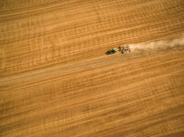 Luftaufnahme eines Traktors, der nach der Ernte ein Feld bearbeitet — Stockfoto