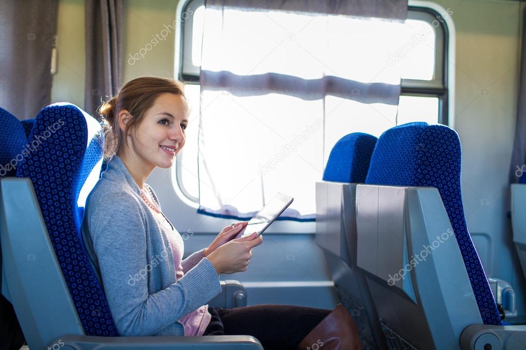 Young woman using her tablet computer while traveling by train