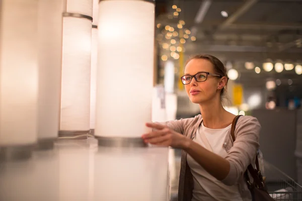 Pretty, young woman choosing the right light for her appartment — Stock Photo, Image