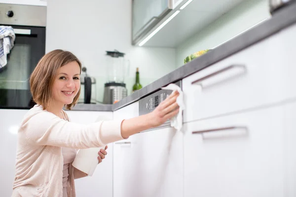 Ung kvinna som gör hushållsarbete, städar köket — Stockfoto