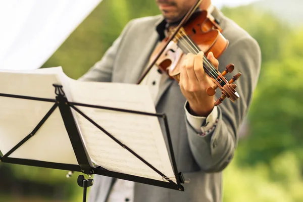 Violinista masculino tocando seu instrumento e lendo uma folha de música — Fotografia de Stock