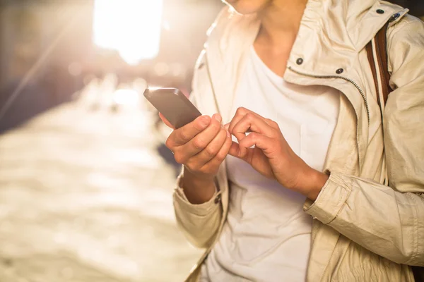 Mensagens de mulher jovem / usando o aplicativo em seu smartphone — Fotografia de Stock