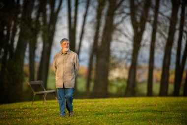 Bir parkta yürüyen bir üst düzey adam açık havada portresi 