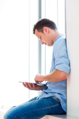 Yakışıklı genç adam onun tablet bilgisayar kullanarak (Renk tonlu görüntü;