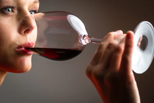 Elegante giovane donna in abito rosso, con un bicchiere di vino rosso — Foto Stock