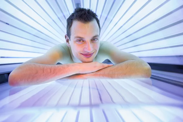 Bello giovane uomo che si rilassa durante una sessione di abbronzatura in un solarium — Foto Stock