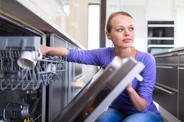 Huishouden: jonge vrouw zet borden in de vaatwasser — Stockfoto