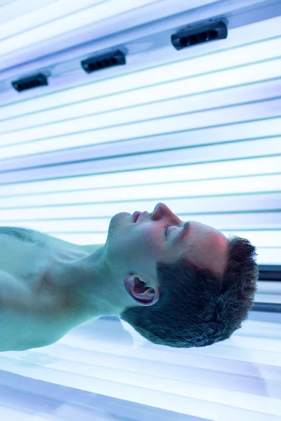 Schöner junger Mann entspannt sich während einer Bräunungssession im Solarium — Stockfoto