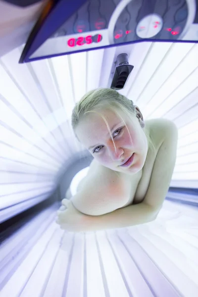 Pretty young woman tanning her skin in a modern solarium — Stock Photo, Image