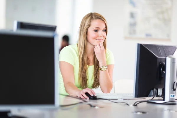 Estudiante guapa y femenina mirando una pantalla de computadora de escritorio — Foto de Stock