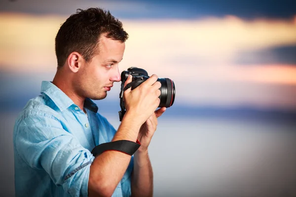 Hermoso joven fotógrafo utilizando su moderna DSLR al aire libre — Foto de Stock