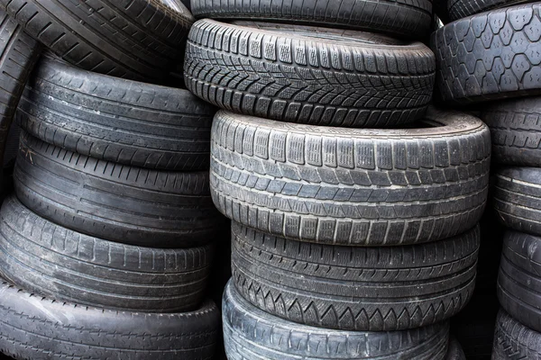 Neumáticos para la venta en una tienda de neumáticos - pilas de neumáticos usados viejos —  Fotos de Stock